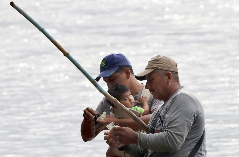 A migrant pays a man after he rafted him and his family across the Suchiate river from Guatemala to the Mexican side of the border, near Ciudad Hidalgo, Mexico, early Tuesday, June 11, 2019. Mexican officials say they are beginning deployment of 6,000 National Guard troops for immigration enforcement, an accelerated commitment made as part of an agreement with the United States last week to head off threatened U.S. tariffs on imports from Mexico. (AP Photo/Marco Ugarte)