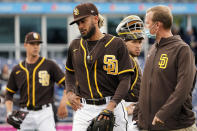 San Diego Padres shortstop Fernando Tatis Jr., center, leaves the field following an injury in the third inning of a spring training baseball game against the Cincinnati Reds Tuesday, March 23, 2021, in Peoria, Ariz. (AP Photo/Sue Ogrocki)