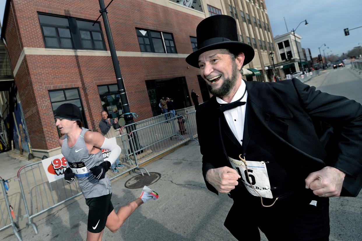 Lincoln actor Michael Krebs  of Chicago, right, runs the last few yards with Tyler Pence of Springfield before Pence crosses the finish line first with a time of 1 hour, 5 minutes, and 56 seconds winning the Lincoln Presidential Half Marathon Saturday April 2, 2022. [Thomas J. Turney/The State Journal-Register]