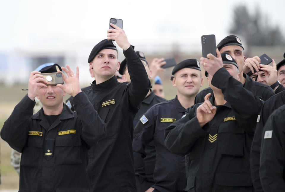 Albanian soldiers take photographs as Italian Eurofighters fly over, during an inauguration ceremony at an airbase, in Kocuve, about 85 kilometers (52 miles) south of Tirana, Albania, Monday, March 4, 2024. NATO member Albania inaugurated an international tactic air base on Monday, the Alliance’s first one in the Western Balkan region. The air base situated in Kucove 85 kilometers (52 miles) south of Tirana, the capital, is named after the small town of Kuçove nearby. (AP Photo/Armando Babani)