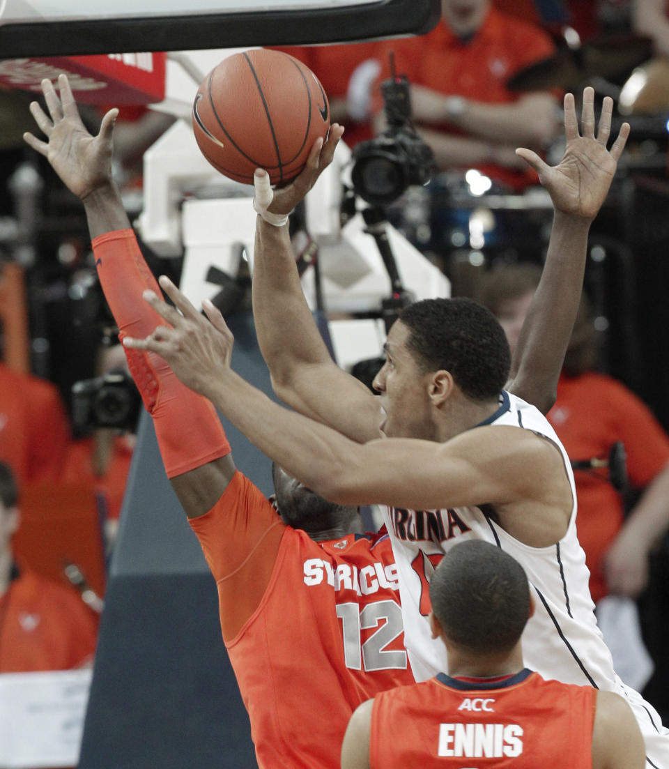 Virginia guard Malcolm Brogdon, center, takes a shot over Syracuse center Baye-Moussa Keita (12) and Syracuse guard Tyler Ennis (11) during the first half of an NCAA College basketball game in Charlottesville, Va., Saturday, March 1, 2014. (AP Photo/Steve Helber)