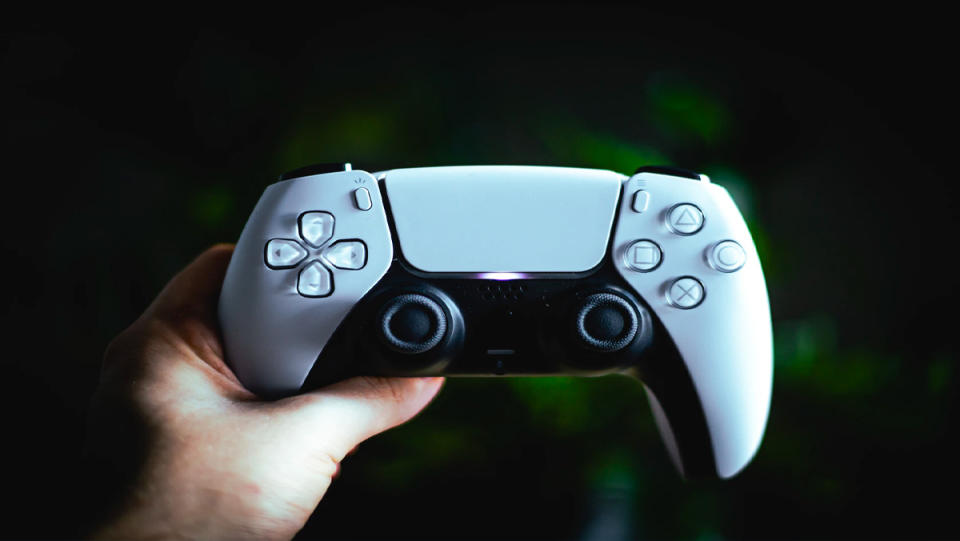 A hand holding a PS5 controller.