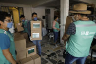 City workers carry medical and food supply kits being taken for home delivery to households with a member suffering from symptoms of COVID-19, in the Coyoacan district of Mexico City, Thursday, April 9, 2020. To help halt the spread of the new coronavirus, the Mexican megalopolis is making home deliveries to households with a symptomatic person, providing kits containing food staples, face masks, gloves, antibacterial gel, paracetamol, a thermometer, and benefits cards with a balance of 1000 pesos (around $42). (AP Photo/Rebecca Blackwell)