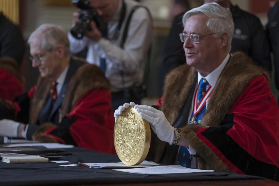 A 15-kilogram (33-pound) gold coin produced to celebrate the late Queen Elizabeth II's Platinum Jubilee, is assessed during the "Trial of the Pyx,'' a ceremony that dates to the 12th Century in which coins are weighed in order to make certain they are up to standard, at the Goldsmiths' Hall in London, Tuesday, Feb. 7, 2023. A jury sat solemnly in a gilded hall in central London on Tuesday, presided over by a bewigged representative of the crown in flowing black robes, but there were no criminals in the dock. (AP Photo/Kin Cheung)