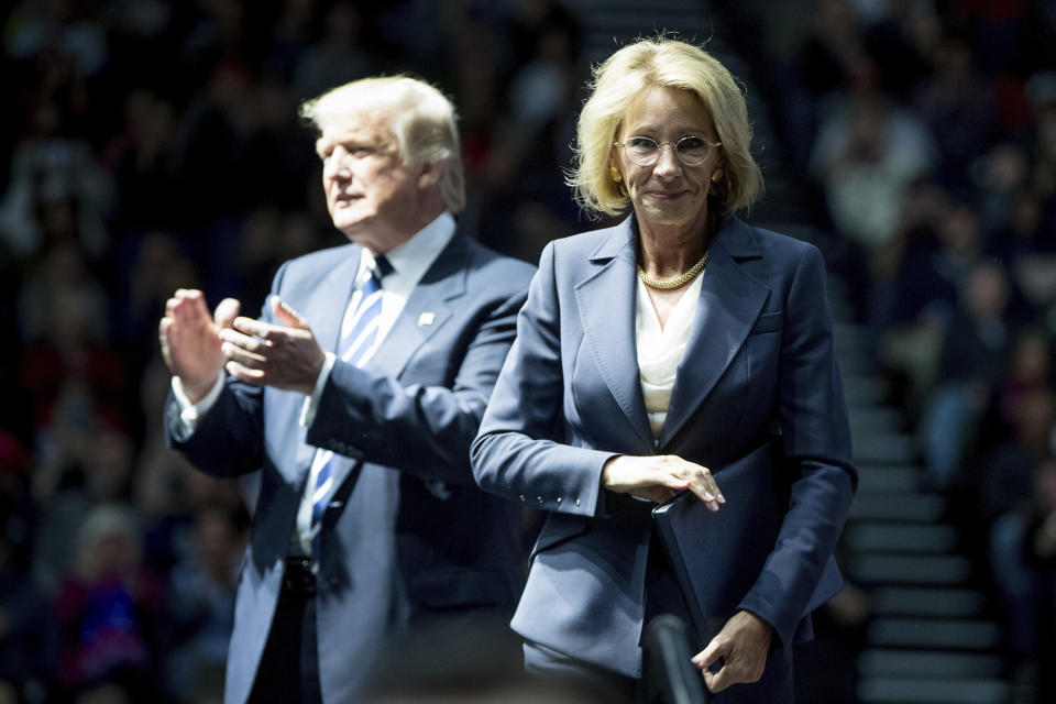 President-elect Donald Trump, left, applauds after his pick for Education Secretary Betsy DeVos, right, finishes speaking at a rally at DeltaPlex Arena, Friday, Dec. 9, 2016, in Grand Rapids, Mich. (AP Photo/Andrew Harnik)