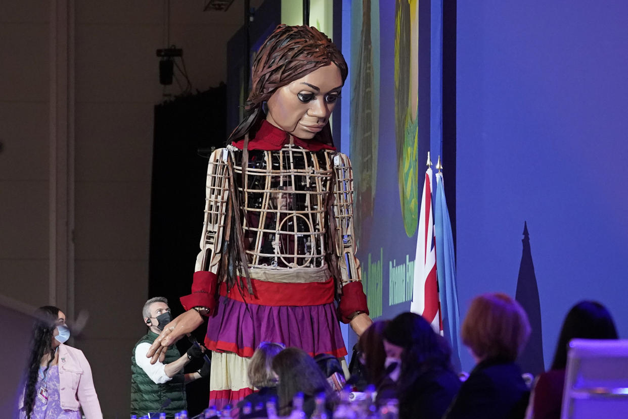 Delegates look up as the giant puppet Little Amal arrives inside the venue of the COP26 U.N. Climate Summit in Glasgow, Scotland, Tuesday, Nov. 9, 2021. The U.N. climate summit in Glasgow has entered it's second week as leaders from around the world, are gathering in Scotland's biggest city, to lay out their vision for addressing the common challenge of global warming. (AP Photo/Alberto Pezzali)