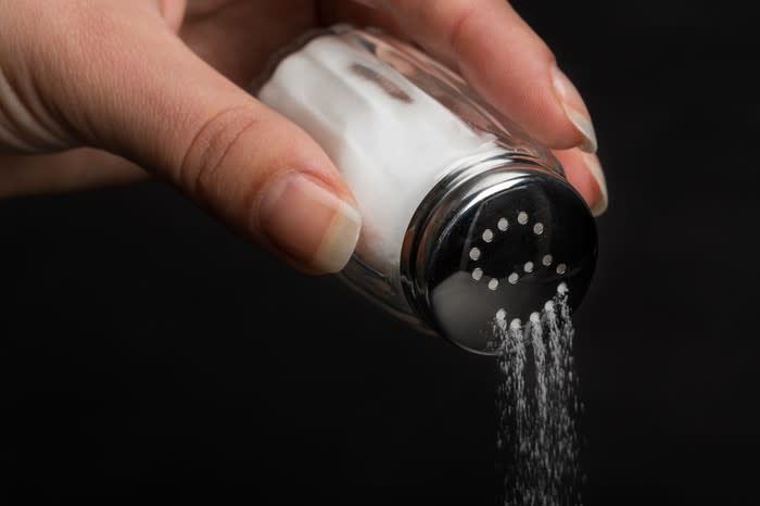Hand pouring salt out of a shaker