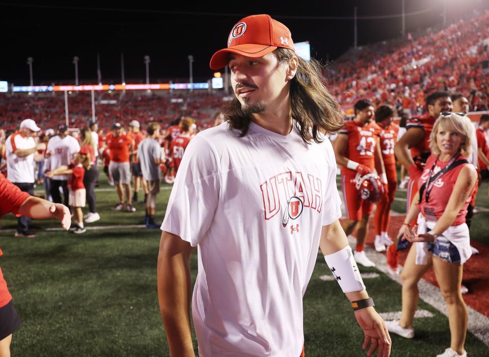 Injured Utah Utes quarterback Cameron Rising (wearing white) walks off the field