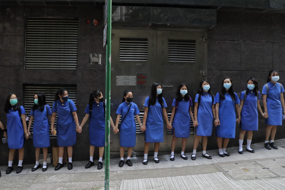 Students wearing mask hold hands to surround St. Stephen's Girls' College in Hong Kong, Monday, Sept. 9, 2019. Thousands of demonstrators in Hong Kong urged President Donald Trump to "liberate" the semiautonomous Chinese territory during a peaceful march to the U.S. Consulate on Sunday, but violence broke out later in the business and retail district as police fired tear gas after protesters vandalized subway stations, set fires and blocked traffic. (AP Photo/Kin Cheung)