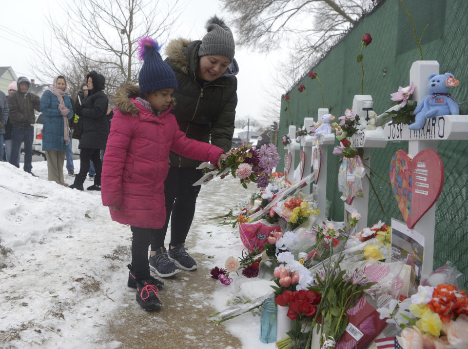 Mourners place a flower at the crosses outside of the Henry Pratt company in Aurora on Sunday, Feb. 17 in memory of the 5 employees killed on Friday.(Jeff Knox/Daily Herald via AP)