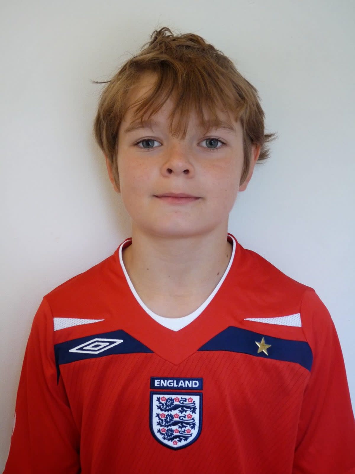 Christian poses as a child in his England top; his mother is from Canterbury and, after his funeral at Brabourne Church of England, he was buried with his grandmother (The Glass Family)