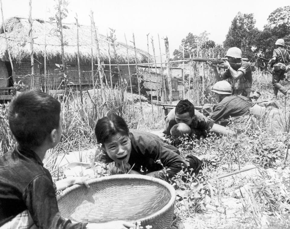 FILE - In this April 1965 under sniper fire, Vietnamese civilians duck for safety as U.S. Marines storm the village of My Son, near Da Nang in Vietnam searching for Viet Cong insurgents. The Vietnamese capital once trembled as waves of American bombers unleashed their payloads, but when Kim Jong Un arrives here for his summit with President Donald Trump he won’t find rancor toward a former enemy. Instead, the North Korean leader will get a glimpse at the potential rewards of reconciliation. (AP Photo/Eddie Adams, File)