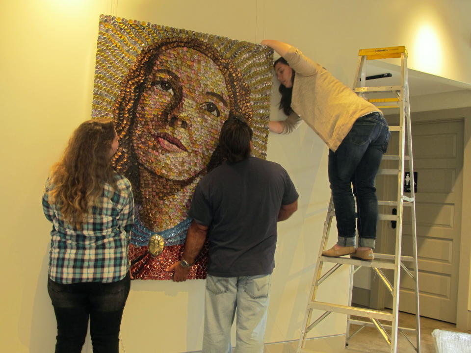 Workers hang a painting in a renovated building in Lake City, S.C., as part of the ArtFields arts festival on Thursday, April 18, 2013. The 10-day arts festival runs from April 19 through April 28, 2013. Many of the 400 works of art are being displayed in businesses in this old tobacco town. (AP Photo/Bruce Smith)