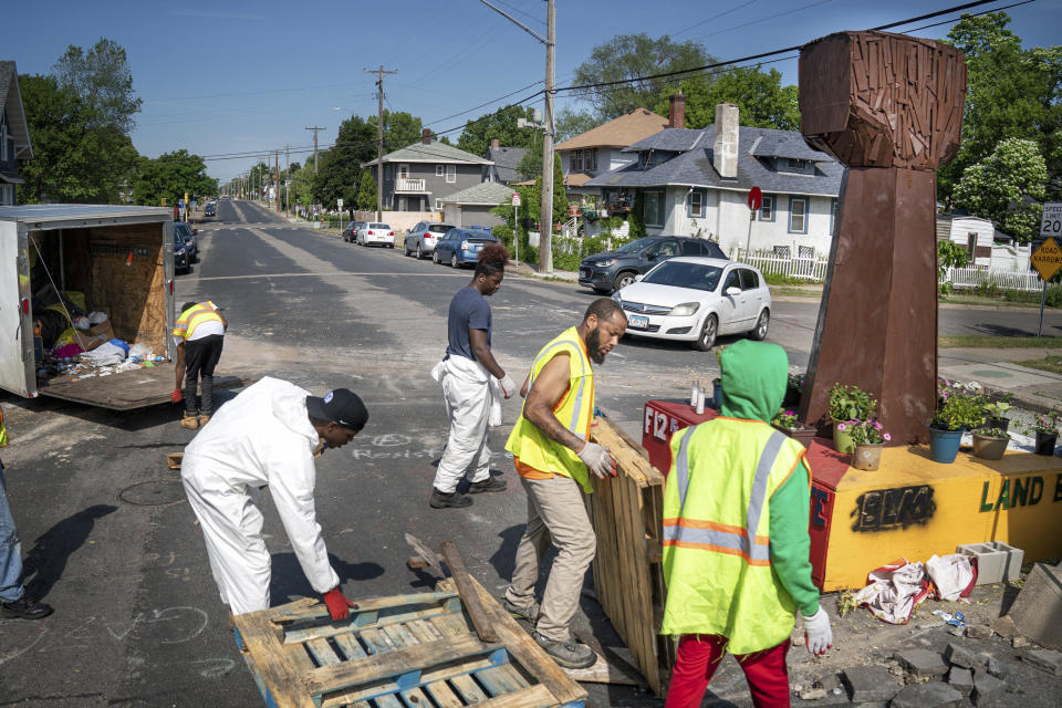 Crews arrive at George Floyd Square and attempted to remove shipping pallets placed on the street to block traffic on Tuesday, June 8, 2021 in Minneapolis. Workers using front-end loaders and brooms arrived just before 5 a.m. Tuesday and cleared the intersection where Floyd was killed, which is informally known as George Floyd Square. (Glen Stubbe/Star Tribune via AP)