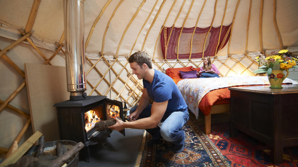  What is winter hot tenting: man putting wood in wood burning stove. 