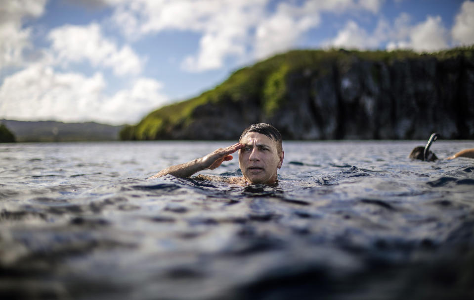 Walter Denton, a former Army sergeant, treads water while saluting a U.S. flag on a nearby cliff of a military base during the morning broadcast of the national anthem as he swims with his brother in Agat, Guam, Saturday, May 11, 2019. "It helped me to stay focus every single day," Denton says of his time in the military and coping with a sexual abuse by a priest over 40 years ago, allegations detailed in a lawsuit. "Every morning I looked forward to putting on my uniform and going to work. It was a distraction." Former Archbishop of Agana, Anthony Apuron denies the allegations. (AP Photo/David Goldman)