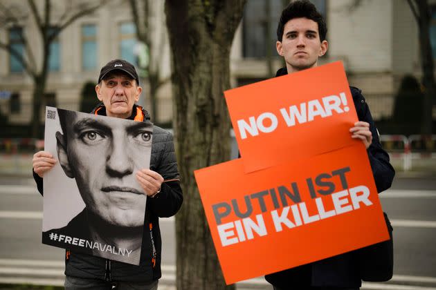 Protesters hold posters with a portrait of Navalny and a sign that reads 