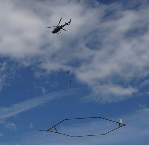 A low-flying helicopter towing a geophysical device collects scientific data for salinity and aquifer mapping.