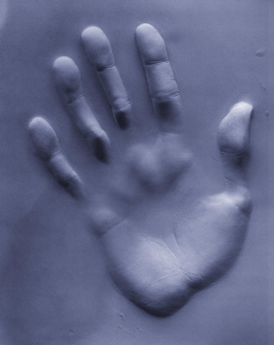 Imprint of a human hand pressed into a soft surface creating a relief effect