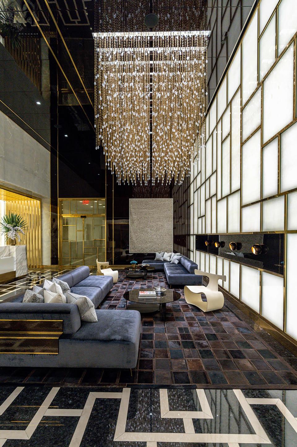 a light fixture hanging over a blue couch and geometric patterned floor in the lobby of luxury skyscraper Central Park Tower