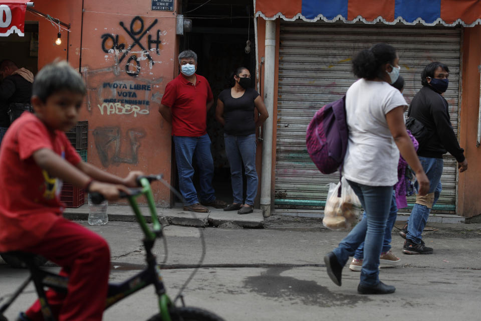 José Juan Serralde y su esposa Blanca Evangelista Villada aparecen en la puerta de entrada a su casa, en San Gregorio Atlapulco, Xochimilco, en Ciudad de México, el miércoles 29 de julio de 2020. Los padres de Serralde, que vivían con ellos, murieron por COVID-19 en mayo, mientras que ellos y dos de sus cuatro hijas se contagiaron aunque con síntomas menores. (AP Foto/Rebecca Blackwell)