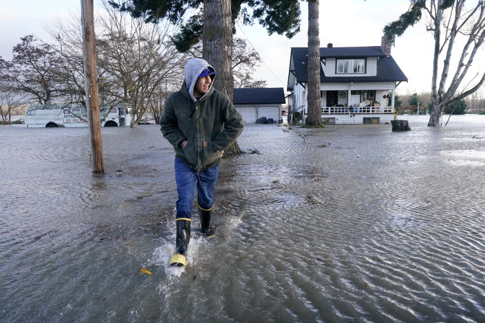 Benjamin Lopez steps from floodwater surrounding his parents home Monday, Nov. 15, 2021, in Sedro-Woolley, Wash. The heavy rainfall of recent days brought major flooding of the Skagit River that is expected to continue into at least Monday evening. (AP Photo/Elaine Thompson)
