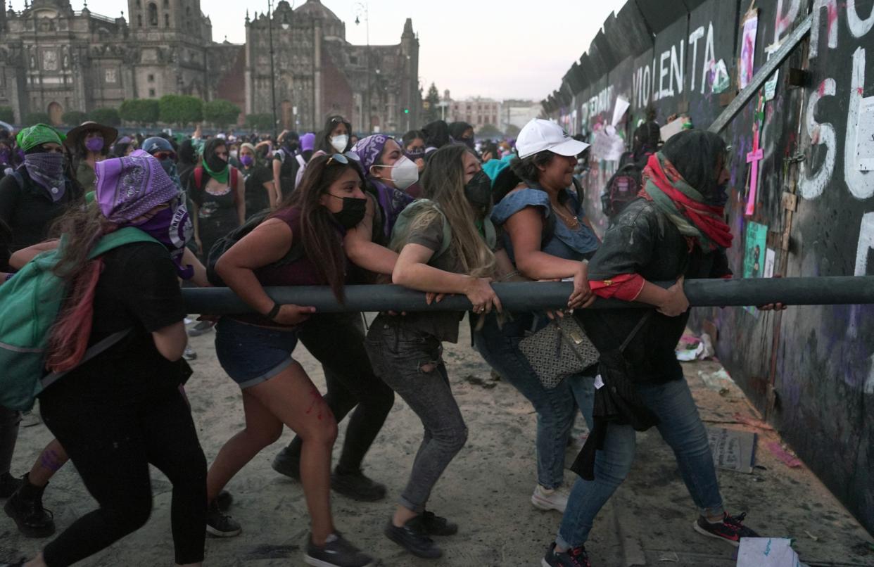 Mujeres tratando de derribar las vallas de protección en Palacio Nacional en Ciudad de México. | Foto: SILVANA FLORES/AFP via Getty Images