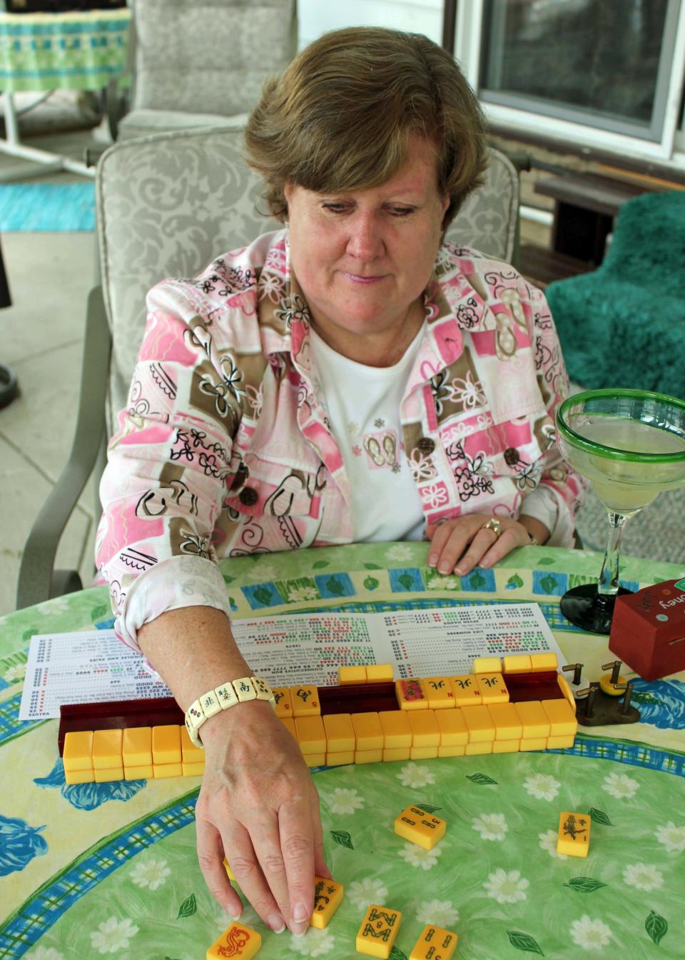 This May 31, 2013 photo shows Judy Palladino handling mahjong pieces during a game night gathering in Mayfield Village, Ohio. For the baby boomer generation, getting together to play games is a way to stay active and social. It also can help people stay mentally sharp. (AP Photo/Bonnie Gruttadauria)