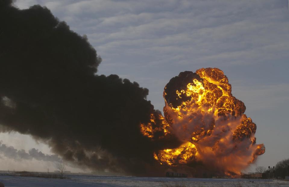 FILE - In this Dec. 30, 2013 file photo, a fireball goes up at the site of an oil train derailment in Casselton, N.D. Railroads that haul volatile crude shipments have reached an agreement with U.S. transportation officials to adopt wide-ranging voluntary safety measures after a string of explosive and deadly accidents. A copy of the agreement between the U.S. Transportation Department and the Association of American Railroads obtained Friday, Feb. 21, 2014 by The Associated Press calls for railroads to slow down oil trains through major cities, increase track inspections and bolster emergency response planning along routes that see trains that can haul up to three million gallons of oil each. (AP Photo/Bruce Crummy, File)