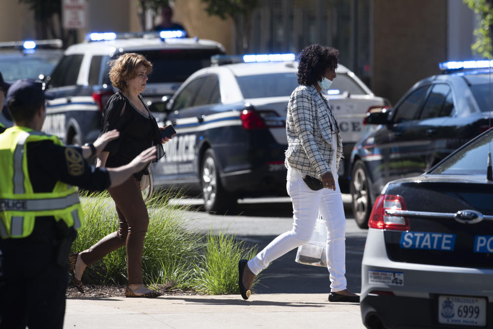 Women walk away from the Tysons Corner Center mall following a shooting inside the shopping center, in Tysons Corner, Va., Saturday, June 18, 2022. (AP Photo/Cliff Owen)