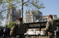 French soldiers patrol along the Notre Dame Cathedral in Paris, Friday, April 19, 2019. Rebuilding Notre Dame, the 800-year-old Paris cathedral devastated by fire this week, will cost billions of dollars as architects, historians and artisans work to preserve the medieval landmark. (AP Photo/Michel Euler)