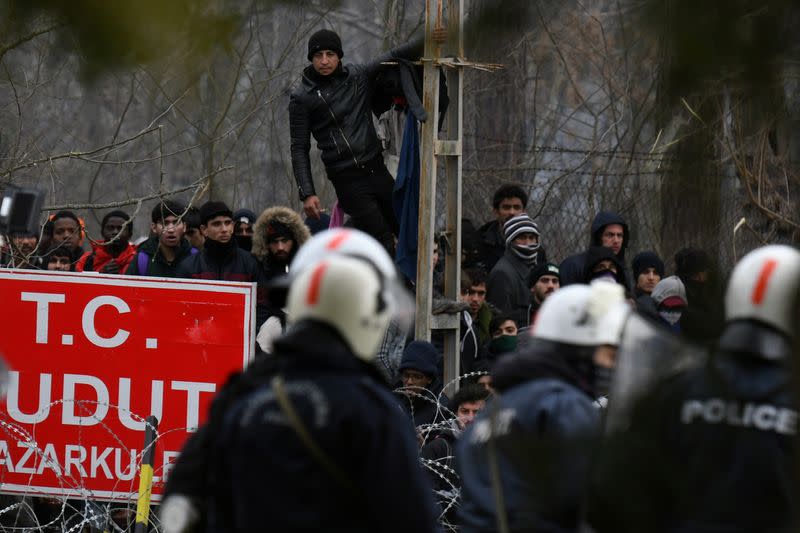 Migrants who want to cross into Greece from Turkey are gathered at the borderline as Greek riot police stand guard at the closed Kastanies border crossing with Turkey's Pazarkule, in the region of Evros