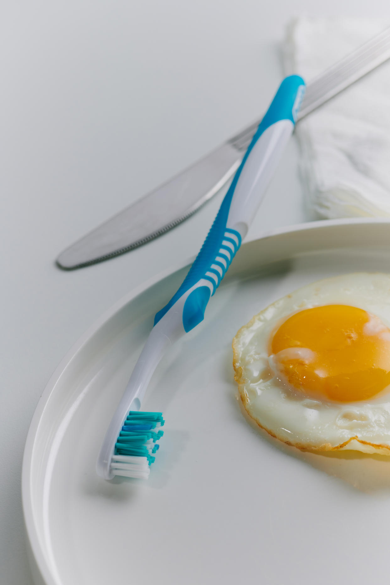 Una ilustración fotográfica de un cepillo de dientes, en lugar de un tenedor, junto a un plato de desayuno, en Nueva York, el 7 de octubre de 2022.  (Aileen Son/The New York Times)