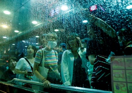 Passers-by watch through a window a rally by civil servants to support the anti-extradition bill protest, during rain in Hong Kong