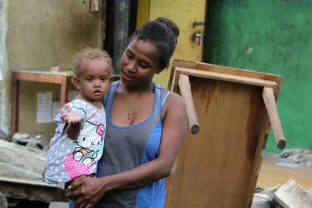 A mother and her child stand near a damaged building in Kirakira on the Solomon Islands after Friday's earthquake, December 10, 2016. Mike Puia/World Vision/Handout via REUTERS