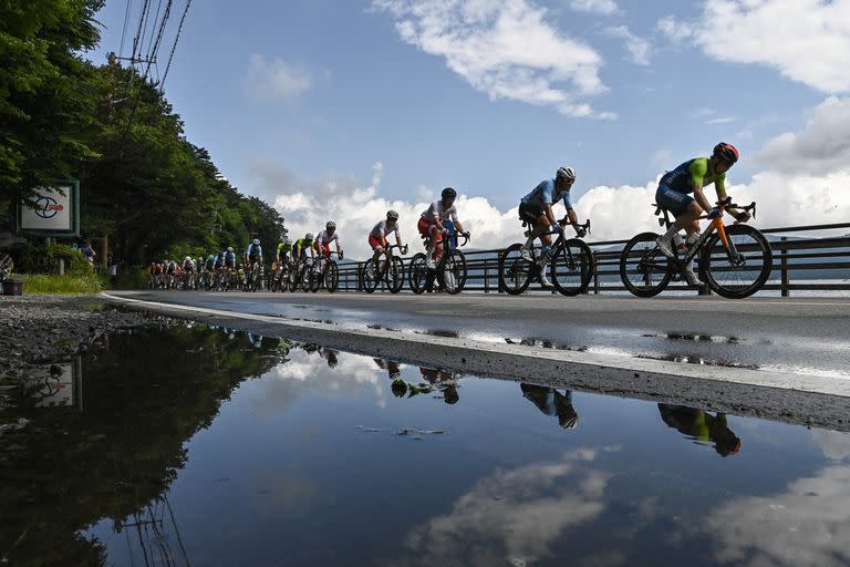 Los ciclistas del pelotón se reflejan en un charco mientras pasan por el lago Yamanaka durante la carrera ciclista en ruta masculina de los Juegos Olímpicos de Tokio 2020 en la prefectura de Yamanashi, Japón, el 24 de julio de 2021.