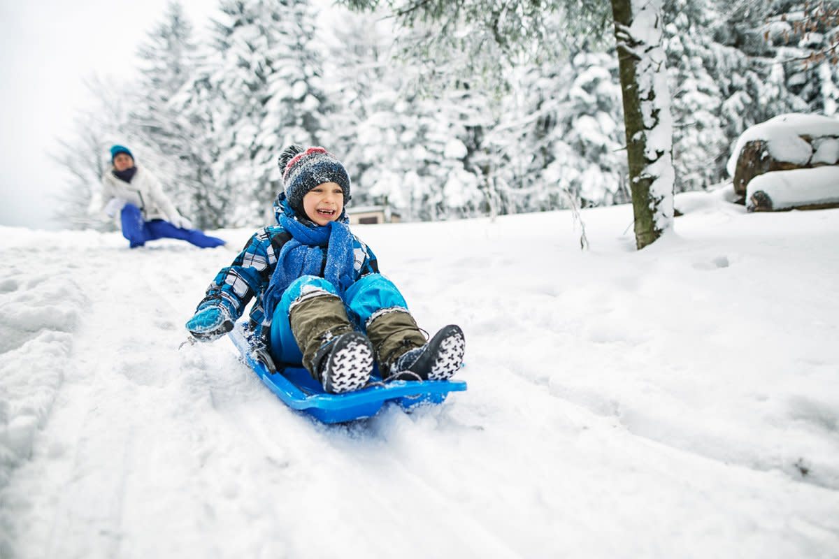A child goes sledding in the snow.