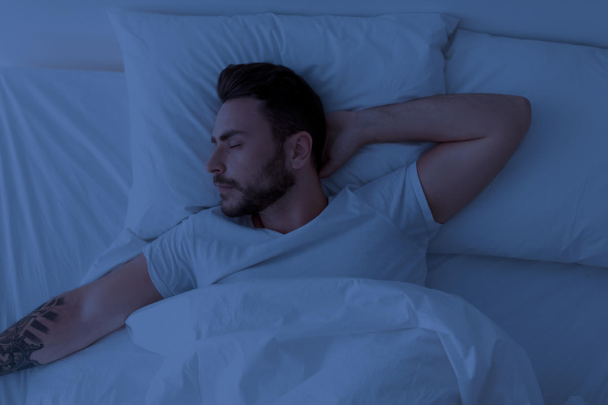 Young man sleeping peacefully at night, lying with closed eyes in comfortable bed in bedroom at home. Healthy male sleep, recreation and wellness