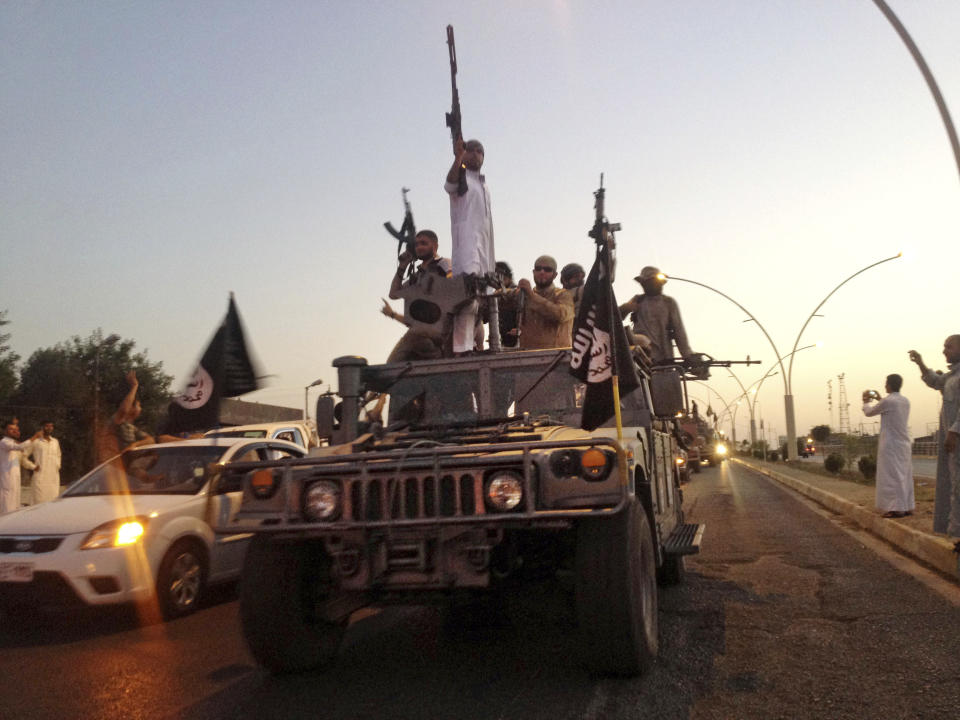 FILE - In this June 23, 2014, file photo, fighters from the Islamic State group parade in a commandeered Iraqi security forces armored vehicle in the northern city of Mosul, Iraq. The IS erupted from the chaos of Syria and Iraq's conflicts and swiftly did what no Islamic militant group had done before, conquering a giant stretch of territory and declaring itself a "caliphate." U.S. officials said late Saturday, Oct. 26, 2019 that their shadowy leader Abu Bakr al-Baghdadi was the target of an American raid in Syria and may have died in an explosion. (AP Photo, File)