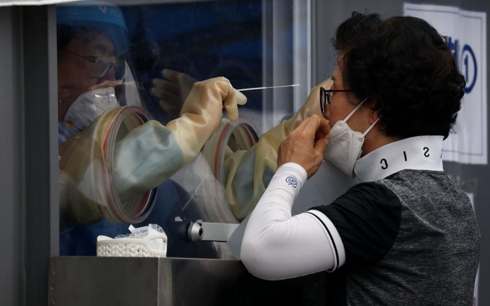 A medical worker takes samples from a woman at a temporary test facility in Seoul - Getty