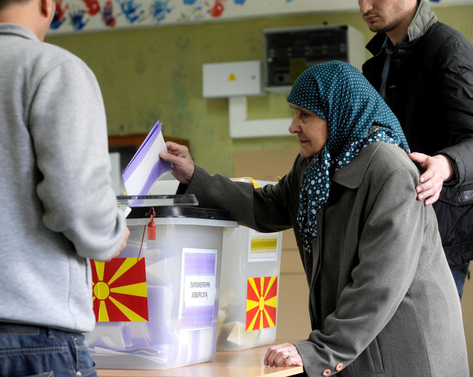 An elderly ethnic Albanian woman is helped to cast her ballot at a polling station in Skopje, Macedonia, on Sunday, April 27, 2014. Macedonia votes Sunday on presidential election runoff and snap parliamentary elections. (AP Photo/Boris Grdanoski)