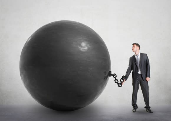 man in suit chained to an enormous black ball