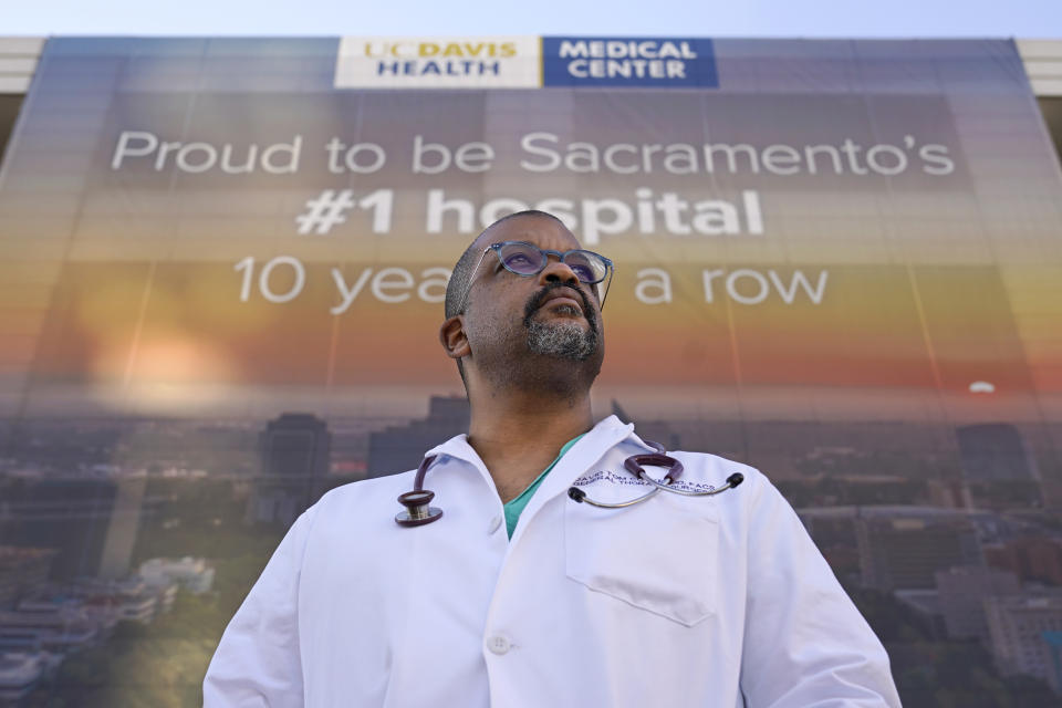 Dr. David Tom Cooke, head of general thoracic surgery at UC Davis Health, poses outside the UC Davis Medical center in Sacramento, Calif., Friday, Dec. 18, 2020. Cooke participated in Pfizer's clinical trial for the coronavirus as part of an effort to reduce skepticism about the vaccine among the Black community. He's now promoting the vaccine's safety and the importance of taking it on his social media pages. (AP Photo/Rich Pedroncelli)