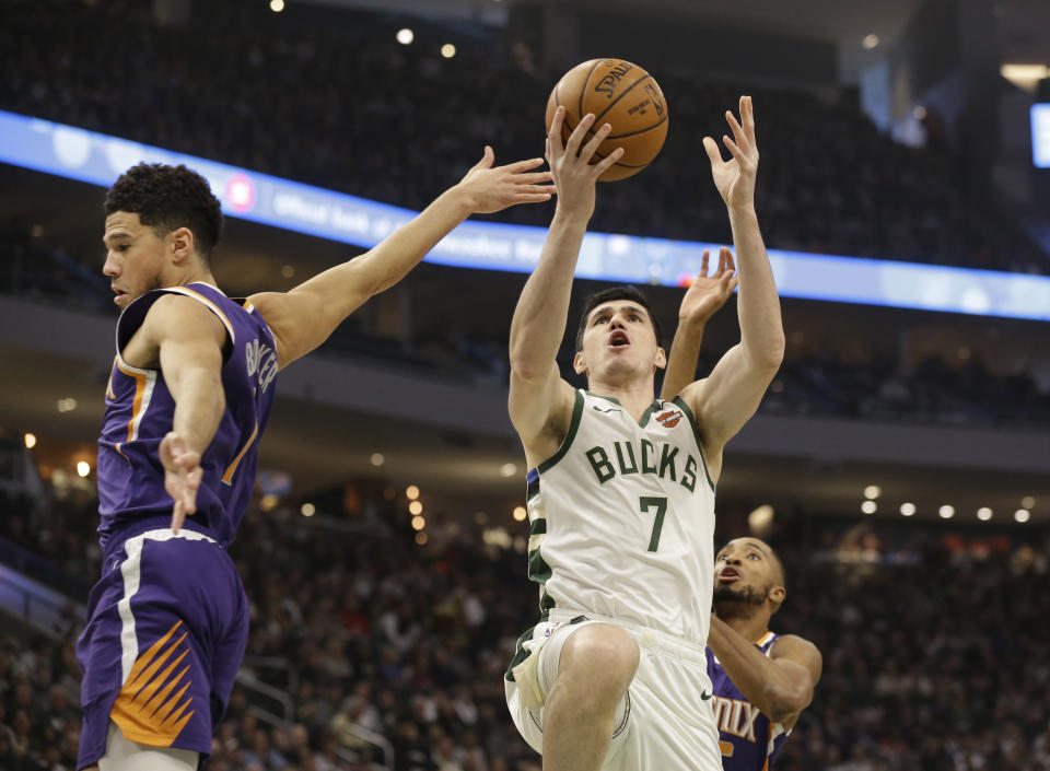 Milwaukee Bucks' Ersan Ilyasova (7) drives against Phoenix Suns' Devin Booker during the first half of an NBA basketball game Sunday, Feb. 2, 2020, in Milwaukee. (AP Photo/Jeffrey Phelps)