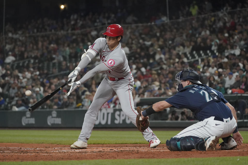 Los Angeles Angels' Shohei Ohtani flies out next to Seattle Mariners catcher Cal Raleigh during the third inning of the second baseball game of a doubleheader Saturday, June 18, 2022, in Seattle. (AP Photo/Ted S. Warren)