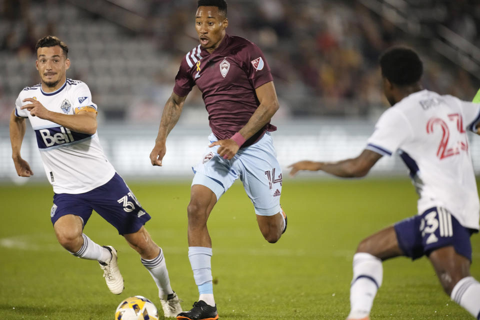 Colorado Rapids midfielder Mark-Anthony Kaye, center, drives with the ball between Vancouver Whitecaps midfielder Russell Teibert, left, and defender Javain Brown in the first half of an MLS soccer match Sunday, Sept. 19, 2021, in Commerce City, Colo. (AP Photo/David Zalubowski)