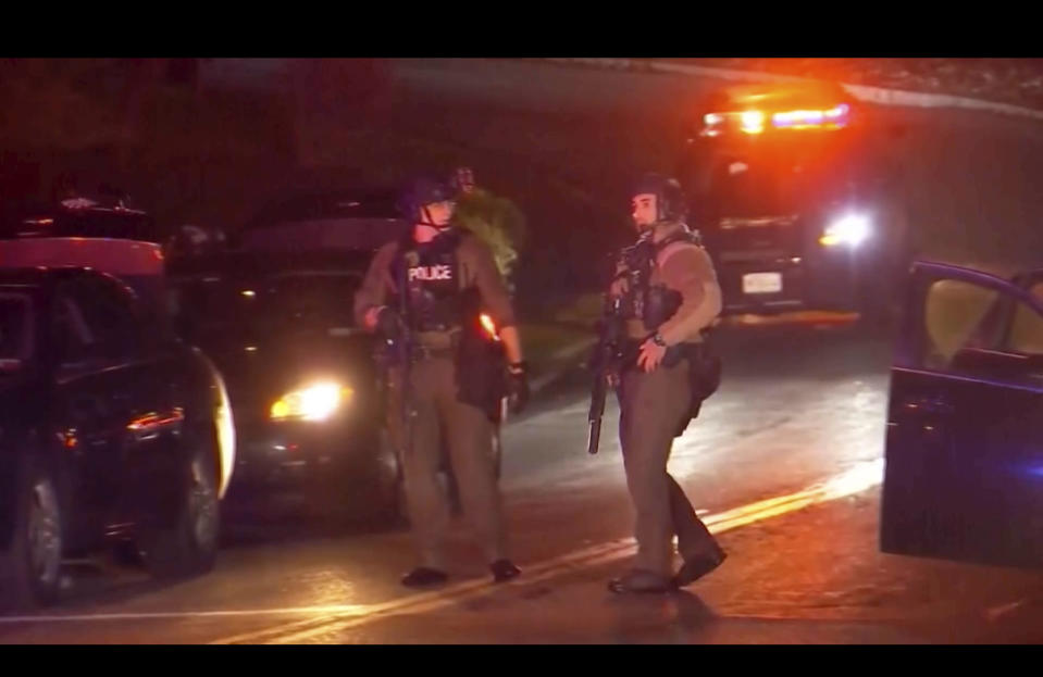 Armed law enforcement officers patrol around the scene of a shooting in Liverpool, N.Y., Sunday, April 14, 2024. A police officer and a sheriff's deputy in upstate New York were shot and killed Sunday night in an exchange of gunfire with a suspect, who also was killed, police said. (WSYR-TV Syracuse via AP)