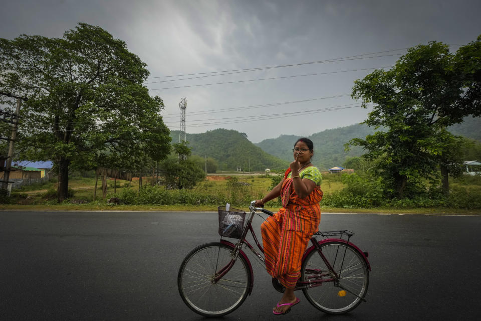 Purnima Boro, 30, a Bodo tribal woman in traditional attire riding a bicycle shows the indelible ink mark on her index finger as she returns after casting her vote during the third phase of general election on the outskirts of Guwahati, India, Tuesday, May 7, 2024. (AP Photo/Anupam Nath)