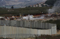 In this Thursday, Dec. 13, 2018 photo, Israeli military equipment works on the Lebanese-Israeli border, next to a wall that was built by Israel, in the southern village of Kafr Kila, Lebanon. As Israeli excavators dig into the rocky ground, Lebanese across the frontier gather to watch what Israel calls the Northern Shield operation aimed at destroying attack tunnels built by Hezbollah. But Lebanese soldiers in new camouflaged posts, behind sandbags, or inside abandoned homes underscore the real anxiety that any misstep could lead to a conflagration between the two enemy states that no one seems to want. (AP Photo/Hussein Malla)