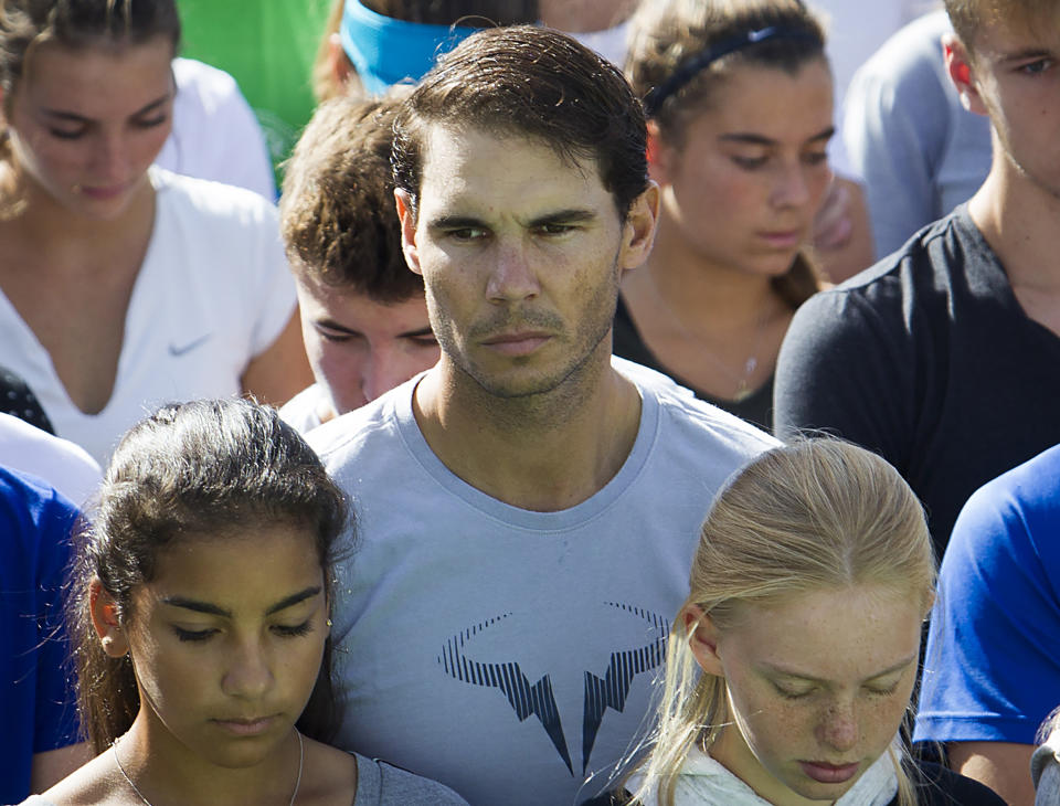 Spanish tennis player Rafa Nadal (c) observes a minute of silence on October 11, 2018 with students and workers of the "Rafa Nadal Academy" in Manacor to honour the victims of the flash flood that affected the Spanish Balearic island of Majorca. - Hundreds of rescue workers searched desperately today for a five-year-old boy and two Germans still missing on Spain's holiday island of Majorca after flash floods tore through streets and swept away cars, killing 10 people. (Photo by JAIME REINA / AFP)        (Photo credit should read JAIME REINA/AFP via Getty Images)